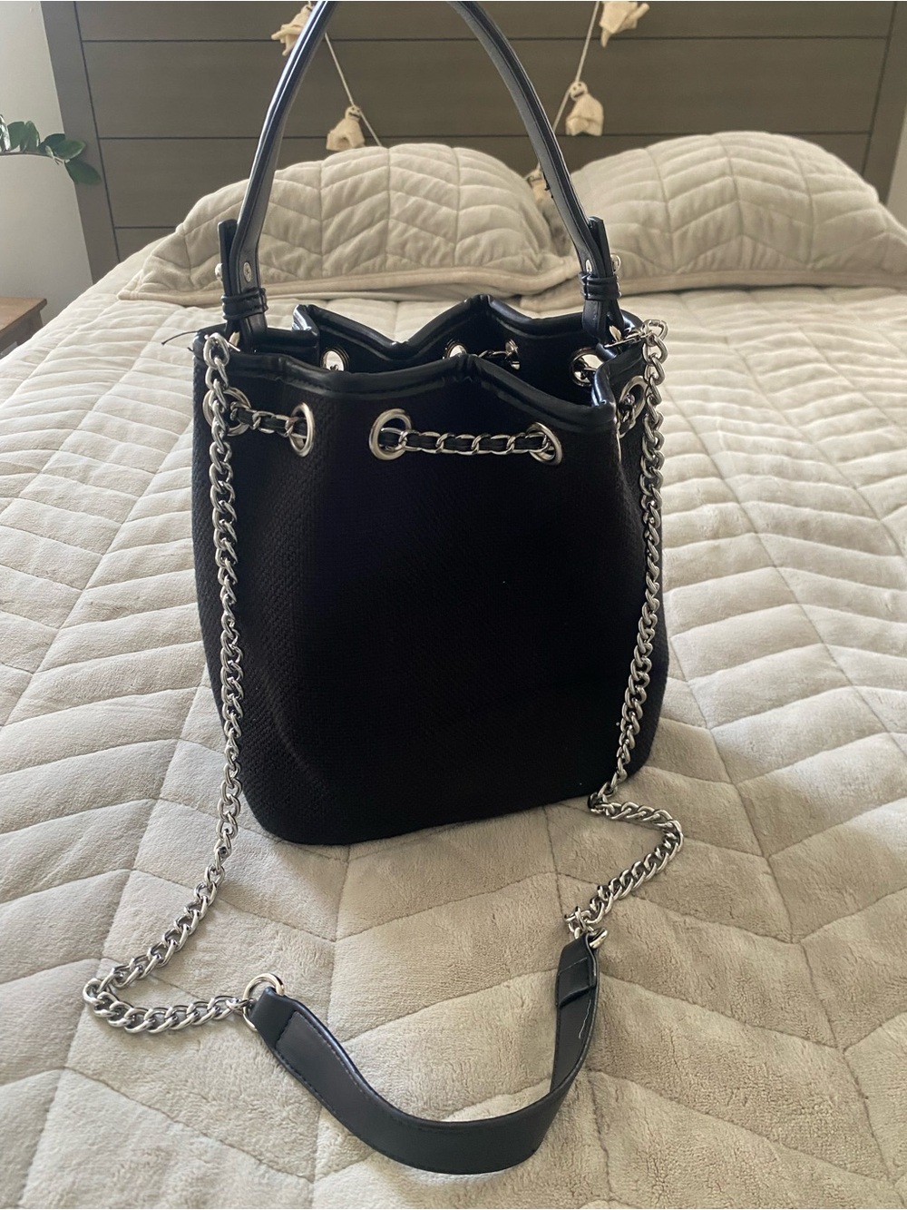 Small black bucket bag. Made of a weave material.